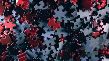 Background of Colored Puzzle Pieces that Slowly Rotating Counterclockwise - Top View. Texture of Incomplete Red and Grey Jigsaw Puzzle with Low Key Light - Left Rotation video