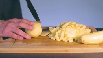 Chef in Black Uniform is Slicing Raw Potato. Man in a Kitchen is Cutting Potato and Preparing Ingredients for Cooking - Slow Motion. Static Shot video