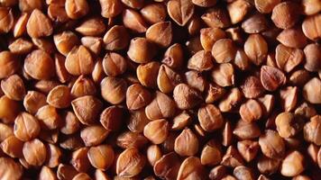 Dry Uncooked Brown Buckwheat Groats, Rotating Background - Top View, Close-Up, Macro. Raw Large Buckwheat Grains. Russian, Ukrainian and Belarusian Culture. Rotation Right video