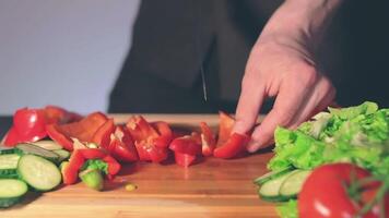 Chef in Black Uniform is Slicing Red Paprika and Preparing Vegetable Ingredients for Cooking. Man in a Kitchen is Cutting Red Pepper for Vegetarian Dish. Healthy Food Concept - Slow Motion video
