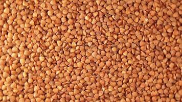 Dry Uncooked Brown Buckwheat Groats, Rotating Background - Top View. Raw Large Buckwheat Grains. Russian, Ukrainian and Belarusian Culture. Rotation Left video