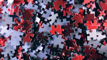 Background of Colored Puzzle Pieces that Slowly Rotating Counterclockwise - Top View. Texture of Incomplete Red and Grey Jigsaw Puzzle with Low Key Light - Left Rotation video