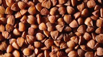 Dry Uncooked Brown Buckwheat Groats, Rotating Background - Top View, Close-Up, Macro. Raw Large Buckwheat Grains. Russian, Ukrainian and Belarusian Culture. Rotation Left video