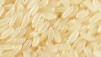 Dry Uncooked Parboiled Rice Background Rotating Clockwise - Top View, Close-Up. Scattered Raw Long Grain Rice. Asian Cuisine and Culture. Healthy Eating Ingredients. Diet Food. Angular Rotation Right video