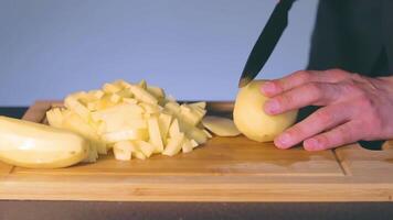 Chef in Black Uniform is Slicing Raw Potato. Man in a Kitchen is Cutting Potato and Preparing Ingredients for Cooking - Slow Motion. Static Shot video