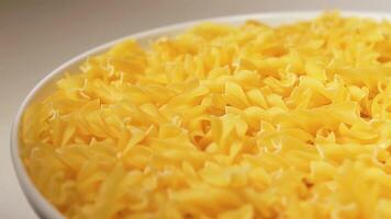 Uncooked Fusilli Pasta on White Plate Rotating against White Background. Fat and Unhealthy Food. Dry Spiral Macaroni. Italian Culture and Cuisine. Raw Golden Pasta video
