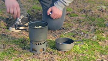 uomo nel un' foresta è cucinando pasta utilizzando un' piccolo cucinare impostare. escursionista nel un' foresta è preparazione per il il pranzo. statico avvicinamento tiro video