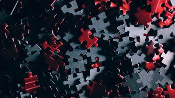 Background of Colored Puzzle Pieces that Slowly Rotating Clockwise - Top View. Texture of Incomplete Red and Grey Jigsaw Puzzle with Low Key Light - Right Rotation video