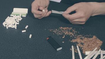 Man in Black Clothing is Rolling a Hand Made Cigarette Using Papers, Filters and Tobacco. A Way to Save on Tobacco Products. Tobacco Product Economy Concept. Top View video