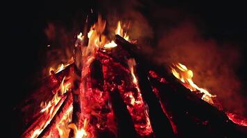 Big Campfire is Burning Down in Early Morning or Evening against the Blue Sky. Wood on Fire. Flying Sparks. Travel and Tourism Concept. Remains of a Giant Bonfire at Summer - Static Shot, Slow Motion video
