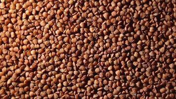 Dry Uncooked Brown Buckwheat Groats, Slowly Rotating Background - Top View, Low Key Light. Raw Large Buckwheat Grains. Russian, Ukrainian and Belarusian Culture. Rotation Left video