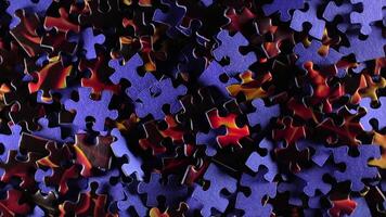 Background of Colored Puzzle Pieces that Slowly Rotating Clockwise - Top View. Texture of Incomplete Red and Blue Jigsaw Puzzle with Low Key Light - Right Rotation video