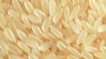 Dry Uncooked Parboiled Rice Background Rotating Counter-Clockwise - Top View. Scattered Raw Long Grain Rice. Asian Cuisine and Culture. Healthy Eating Ingredients. Diet Food. Angular Rotation Left video