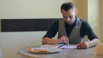 Handsome Young Man is Writing a Document in Pizzeria Cafe. Office Employee Has a Break. Middle Close-Up View, Dynamic Shot video