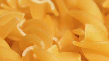 Uncooked Fusilli Pasta Rotating - Macro. Fat and Unhealthy Food. Dry Spiral Macaroni - Close-Up. Italian Culture and Cuisine. Raw Golden Pasta video