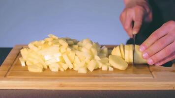 Chef in Black Uniform is Slicing Raw Potato. Man in a Kitchen is Cutting Potato and Preparing Ingredients for Cooking - Slow Motion. Static Shot video