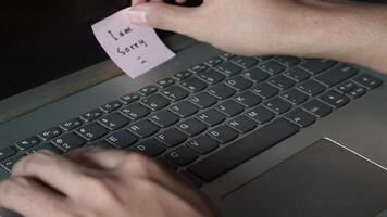Close up man working with this laptop and get motivation sticky note with word I am Sorry video