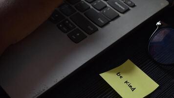 Close up man working with this laptop and get motivation sticky note with word Be Kind video