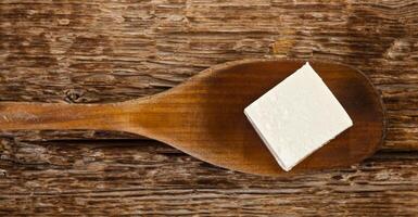 A piece of cheese on a wooden spoon photo
