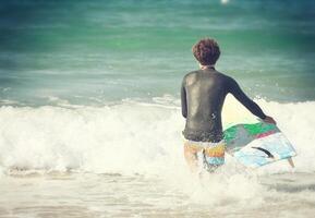 A man in a wet suit holding a surfboard in the ocean photo