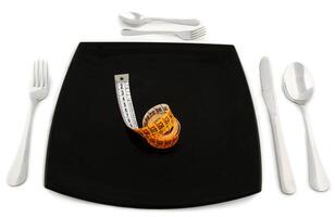 A black plate with a measuring tape, fork, knife and spoon photo