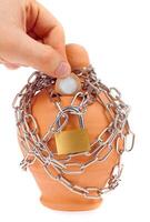A hand holding a coin and chain around a clay pot photo