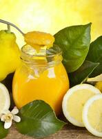 A jar of lemon juice with a spoon and lemons photo