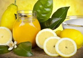 A jar of lemon juice and a bowl of lemon slices photo