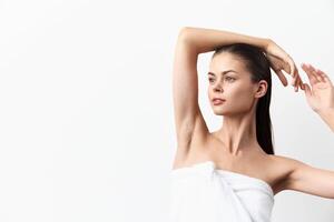 A striking image of a model with long hair and smooth skin, raising her arms while wrapped in a photo
