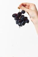 Person holding grapes over white surface with water drop in middle. fresh and vibrant image suitable photo