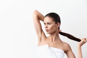 Elegant woman holds her long hair with one hand while the other rests behind her head, exuding photo