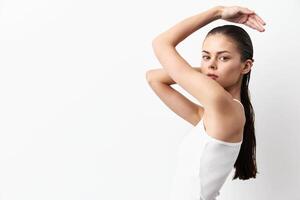 A striking image of a young model with wet hair, posing with her arm raised against a plain white photo