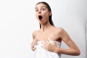Woman surprised with open mouth after shower with wet head in towel on white background. High photo