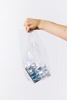 Hand holding full plastic bag of pills on white background. photo