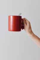 Hand holding red coffee cup with spoon on white background. copy space for message. photo