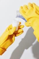 Yellow rubber gloved hands holding bottles of hand sanitizer in a clearing. photo