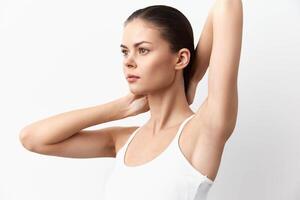 A striking image of a young woman in a sleeveless top, posing with her arms raised, highlighting photo