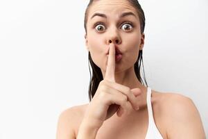The image features a young woman with wet hair making a shushing gesture to convey silence The photo