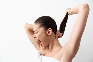 A young woman is captured mid action as she pulls her long hair back, expressing a mix of photo