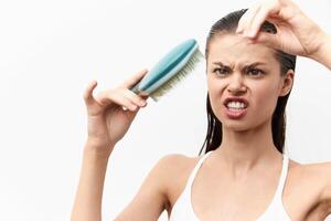 frustrated woman with a hairbrush displaying an unhappy expression, struggling with tangled hair She photo