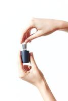 Person holding two perfume bottles, one empty and one full, against a white background. photo
