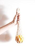 Rope bag with orange inside held by person on white background. photo