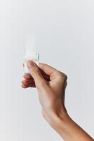 Hand holding small plastic object on white background with empty space in the top left corner for photo