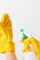 Two women in rubber gloves holding spray bottles with green and yellow nozzles on a white background photo