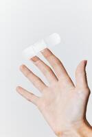 Adhesive bandage being held by a hand on a white background, with blank space for text or image photo