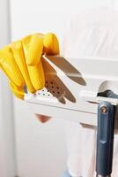 Woman in yellow gloves holding metal piece with paper near other paper pieces. a concept image of a photo