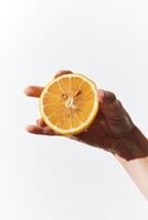 Halved orange slice held by person in front of white background, displaying inside of fruit on both photo