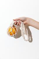 Man holding an orange wrapped in a white rope and cloth. a creative and artistic image of a person photo