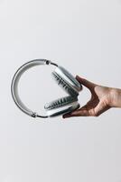 Headphones held by person on white background with copy space in the middle of the image. photo