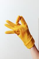 Hand in yellow rubber glove gesturing with thumb and index finger pointing in opposite directions. photo